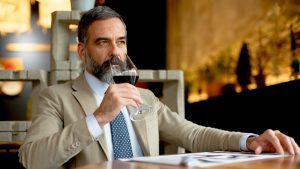 Handsome bearded businessman drinking red wine in restaurant